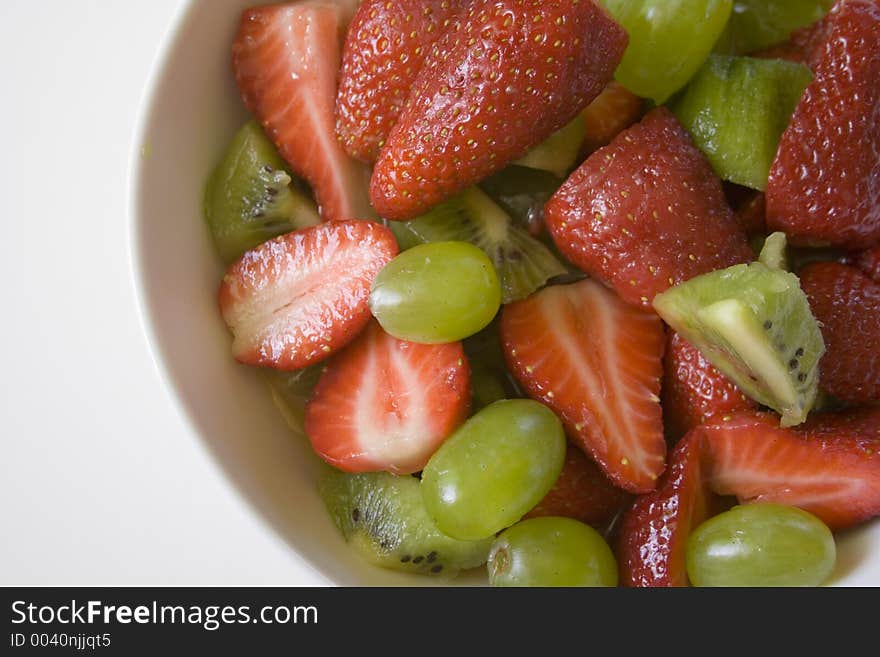 A fresh red and green fruit salad in plain white bowl. A fresh red and green fruit salad in plain white bowl.