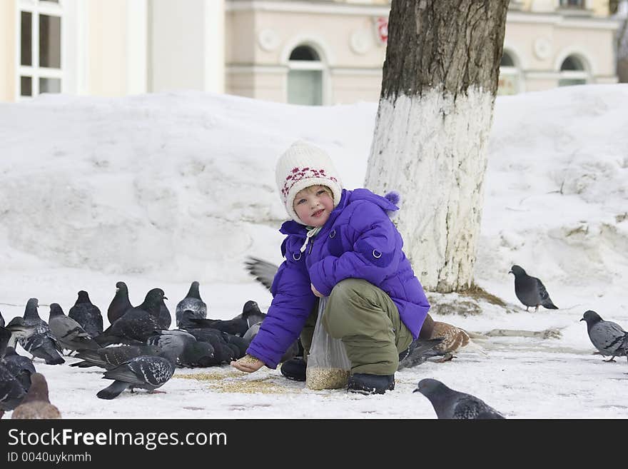 The girl feeds pigeons with pearl barley. The girl feeds pigeons with pearl barley