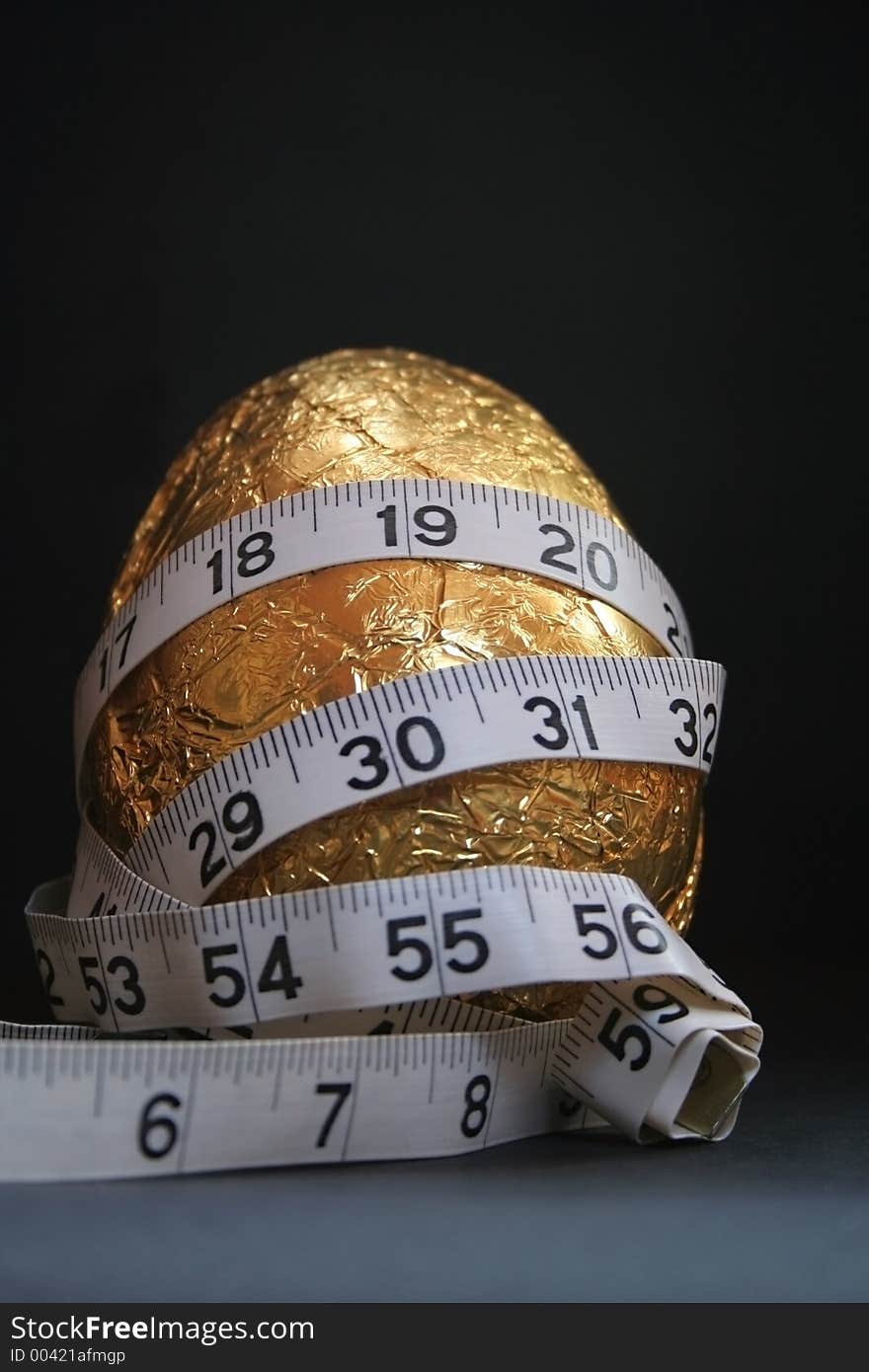 Image of a gold easter egg with a tape measure wrapped around it, conceptual dieting. Image of a gold easter egg with a tape measure wrapped around it, conceptual dieting