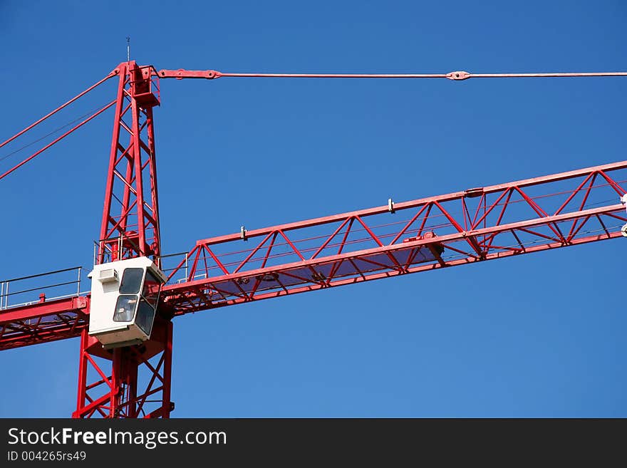 Red construction crane on clear blue sky background