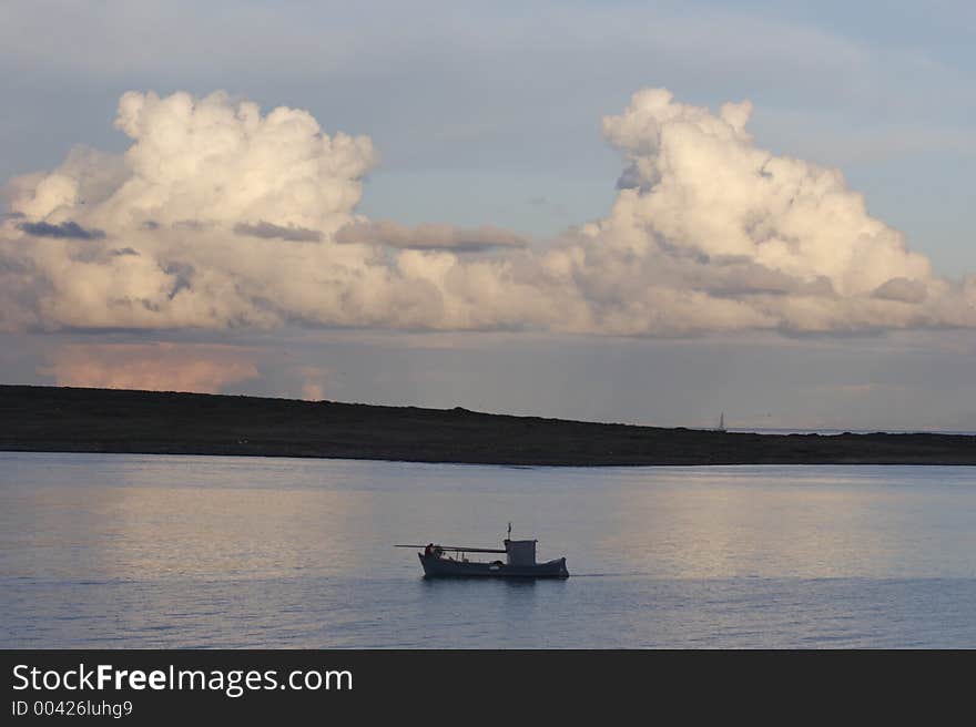 Fishing boat and big cloud in Stintino, Sardinia, Italy