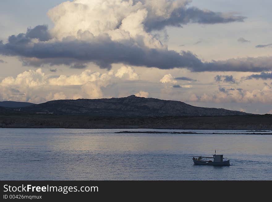 Fishing boat and big cloud on Isola Piana, Stintino, Sardinia, Italy