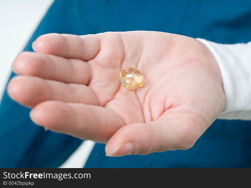 Hand holding two clear gelatin capsules. Hand holding two clear gelatin capsules