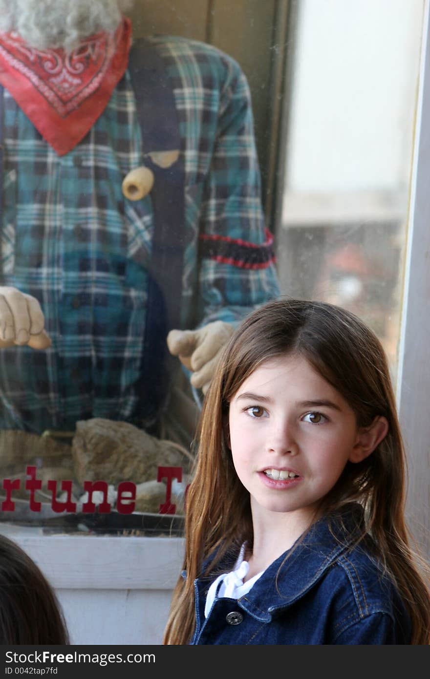 Young girl standing next to a fortune teller booth. Young girl standing next to a fortune teller booth