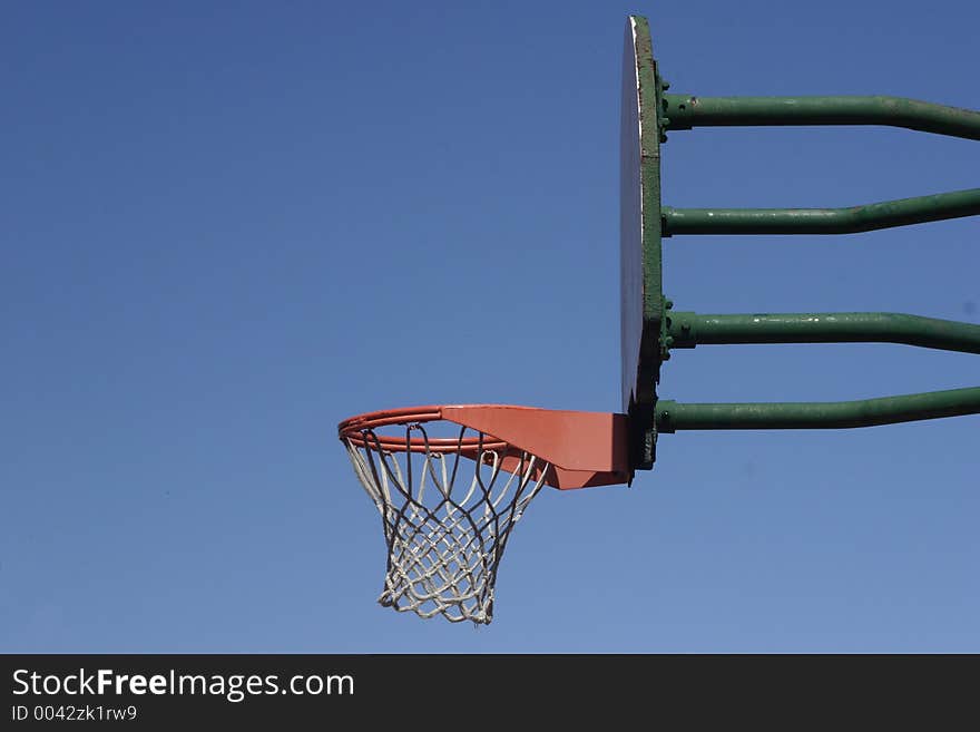 An empty outdoor basketball hoop waits for a ball to hit it. An empty outdoor basketball hoop waits for a ball to hit it