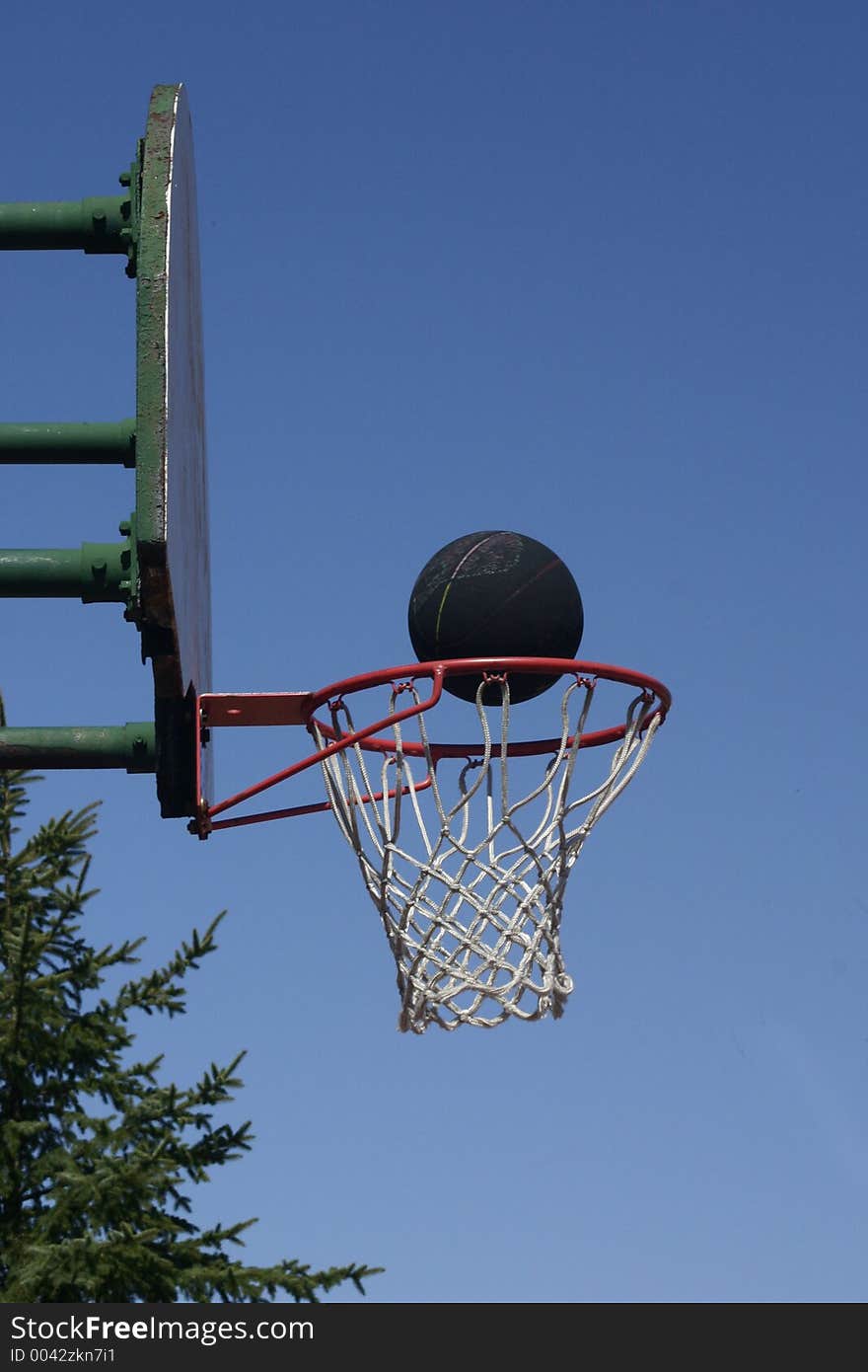 A black basketball rides the basketball rim. A black basketball rides the basketball rim