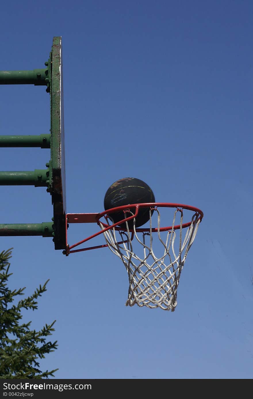 A black basketball sides the rim before sinking in. A black basketball sides the rim before sinking in