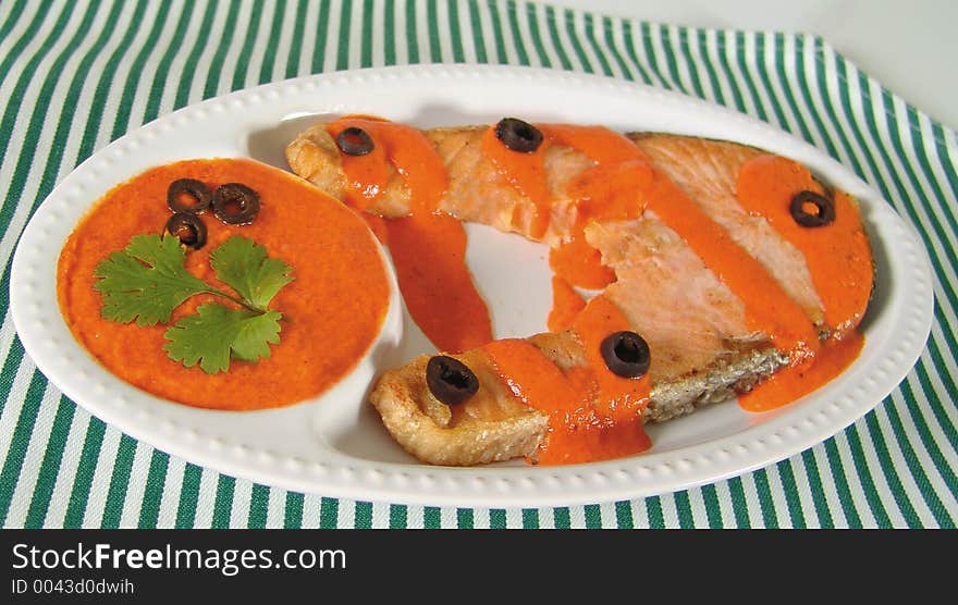 Salmon steak with spicy red sauce and black olives. Salmon steak with spicy red sauce and black olives