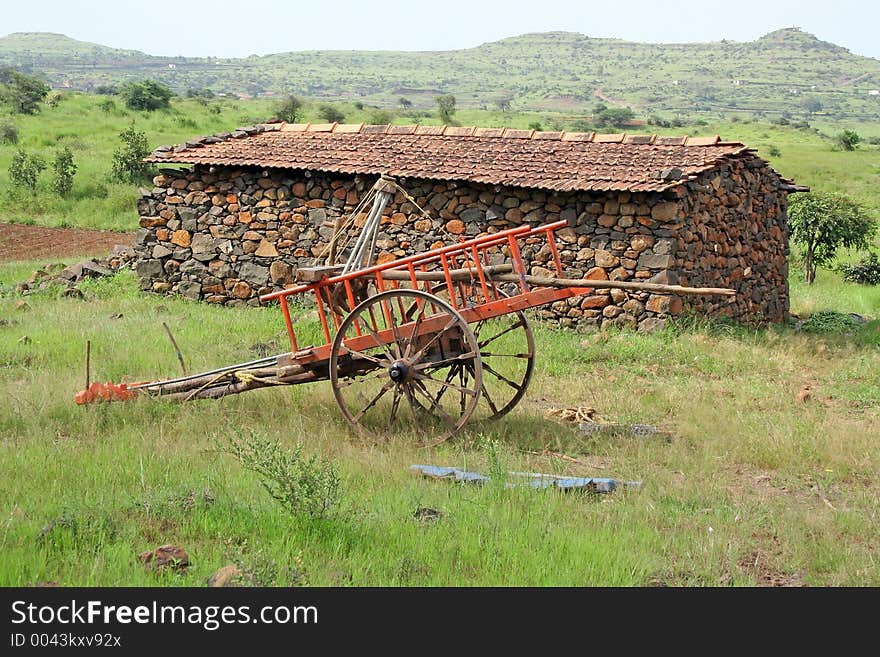 Rural stone and mud hut and painted bullock cart resting in meadow, western India. Rural stone and mud hut and painted bullock cart resting in meadow, western India