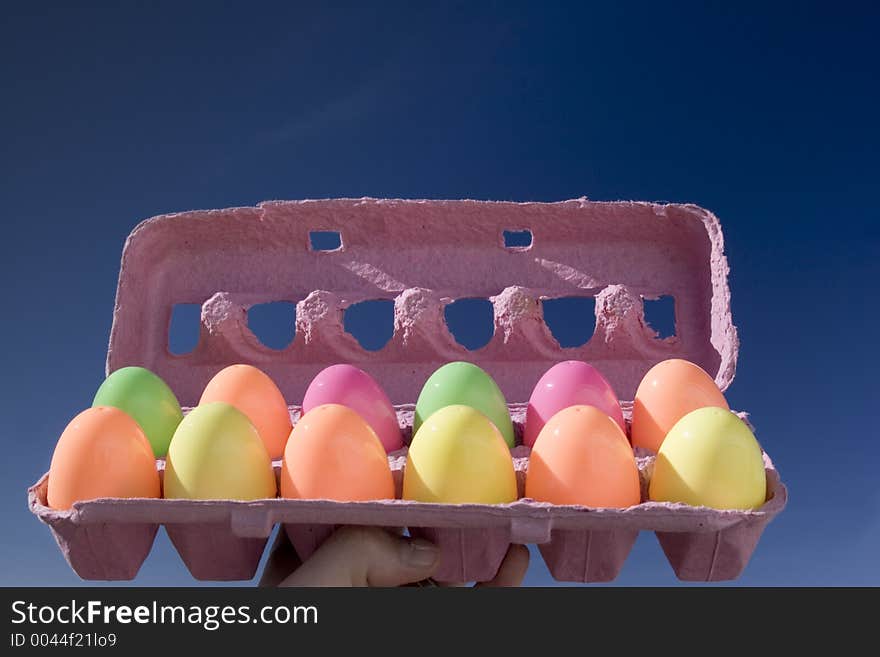 An egg carton with 12 colorful eggs in it. An egg carton with 12 colorful eggs in it