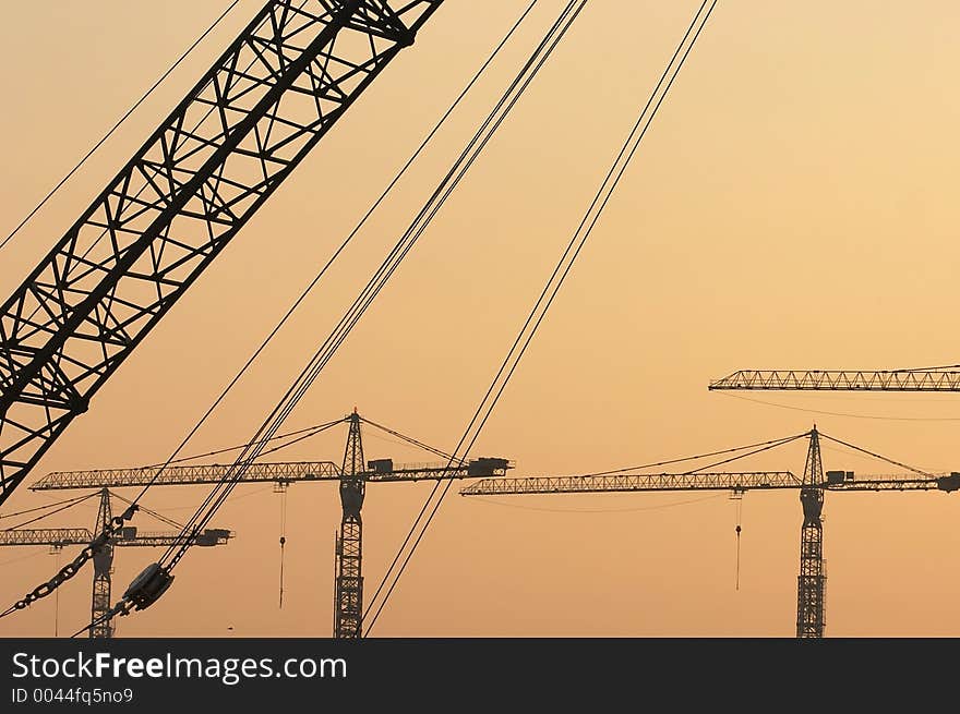 Crane booms against sunset