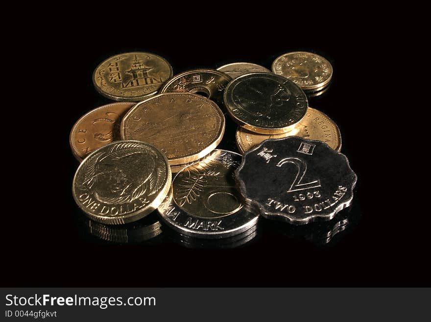 Various foreign coins on reflective black.