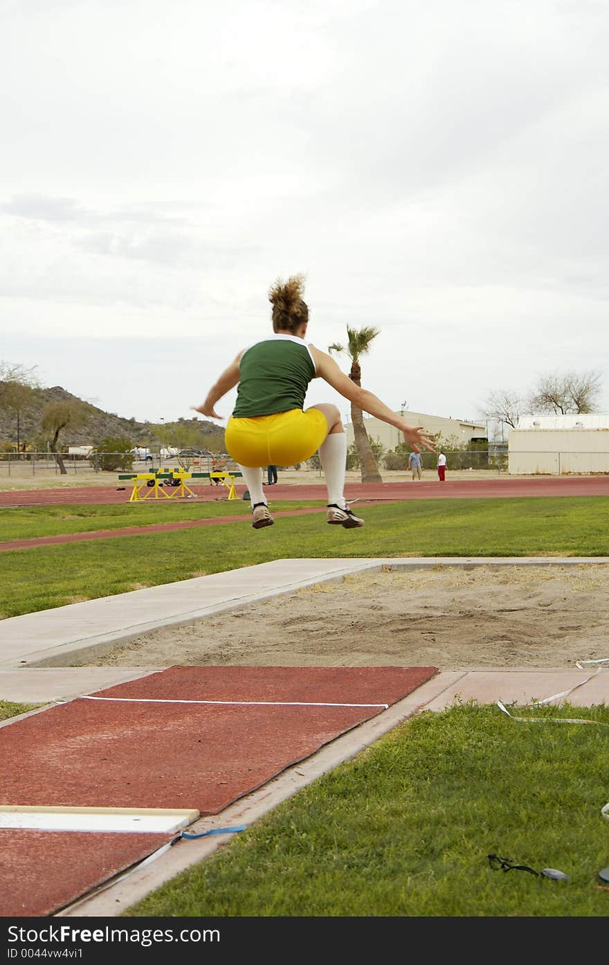 A competitor in the women's long jump event during a college track meet.