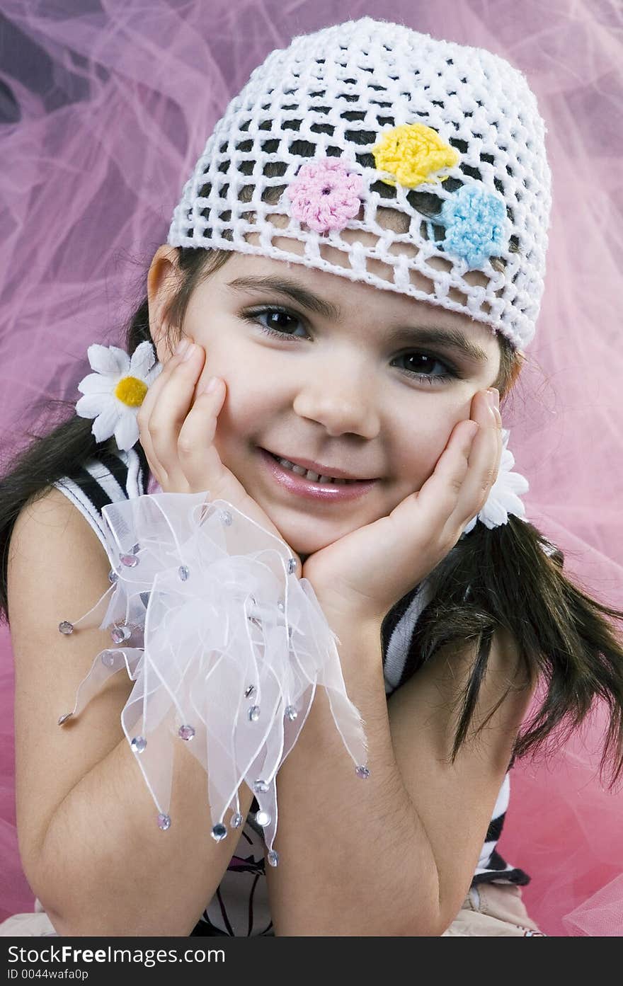 Sweet little girl poses like a spoiled kid in all sorts of new clothes on a pink, veil background