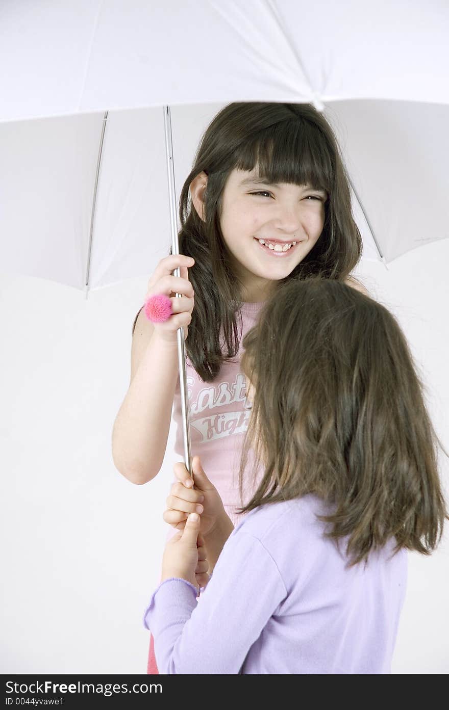 Two little sisters happily sharing an umbrella. Two little sisters happily sharing an umbrella.