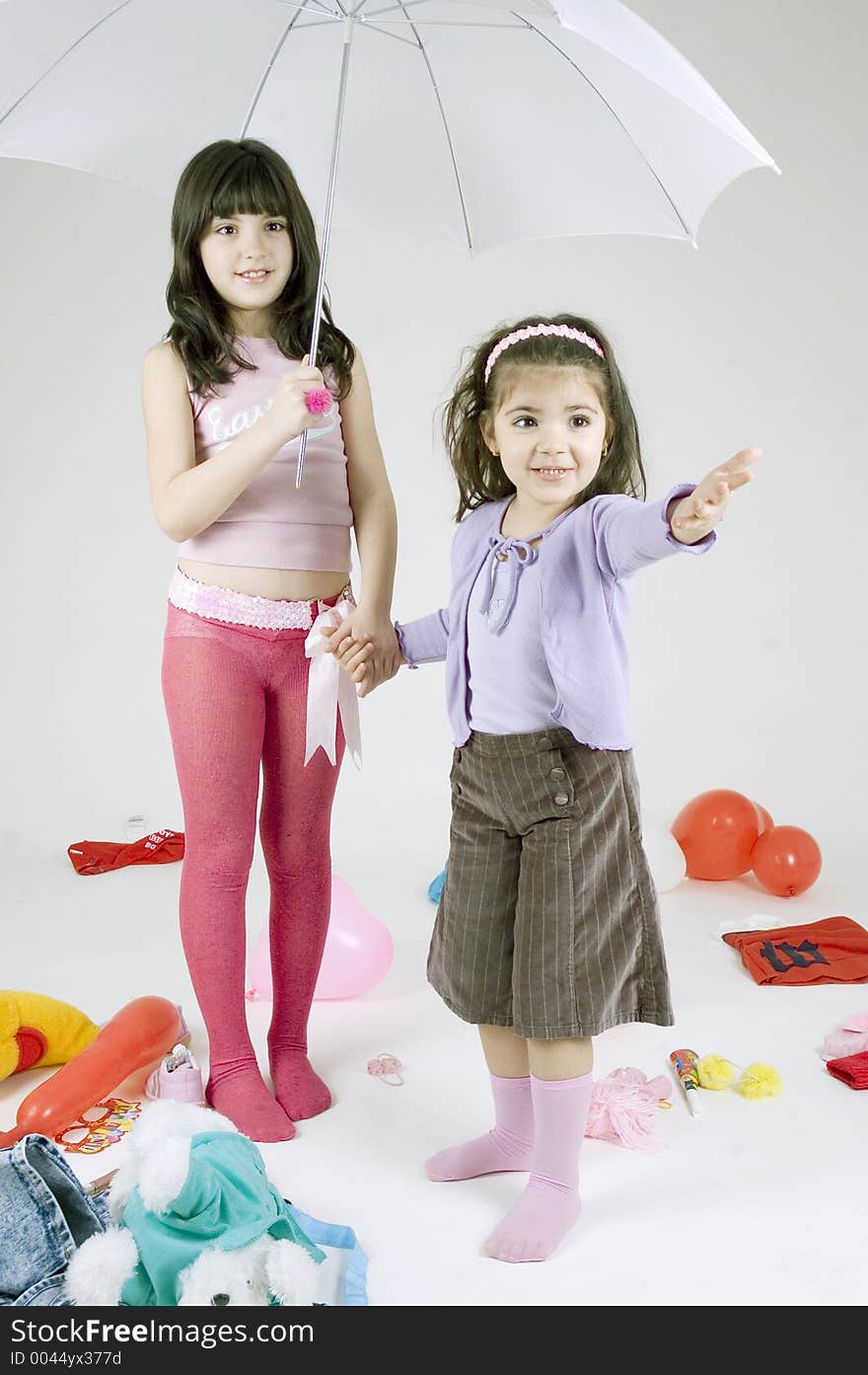 Two cute young sisters playing with an umbrella. Two cute young sisters playing with an umbrella.