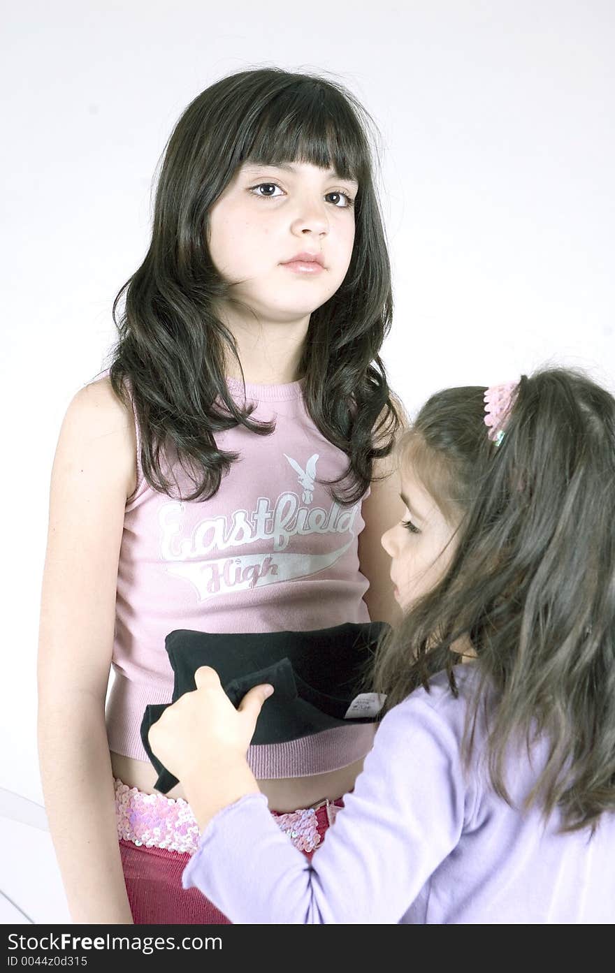 Two cute little girls playing with children's clothes. Two cute little girls playing with children's clothes.