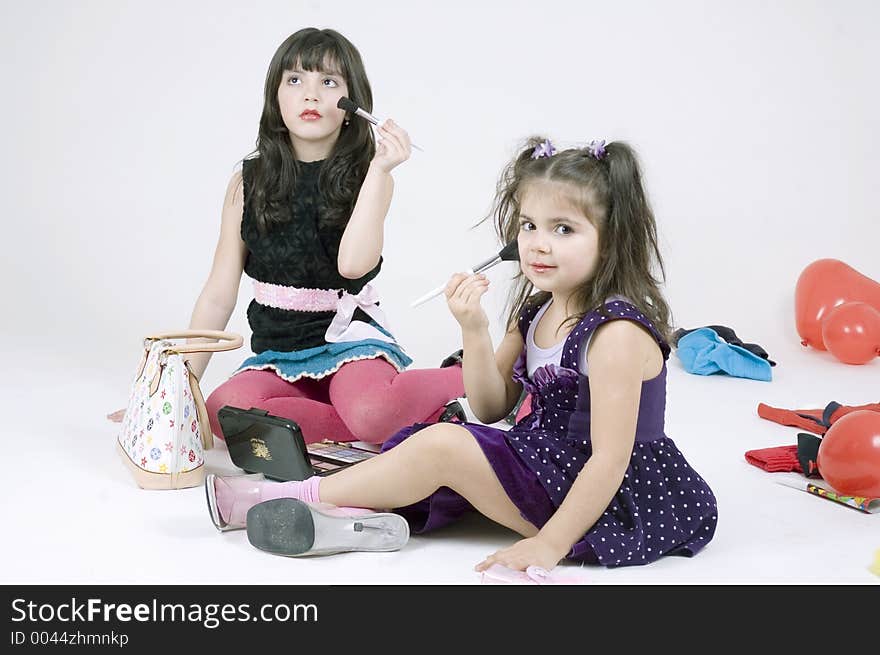 Two little sisters, a seven and a three year old play with make-up, posing as pop-stars, having fun in their roomful of toys. Two little sisters, a seven and a three year old play with make-up, posing as pop-stars, having fun in their roomful of toys