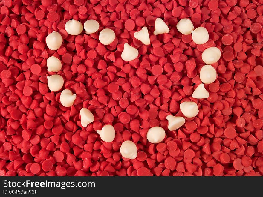 White chocolate chips arranged into a heart shape on a bed of cherry baking chips. White chocolate chips arranged into a heart shape on a bed of cherry baking chips.