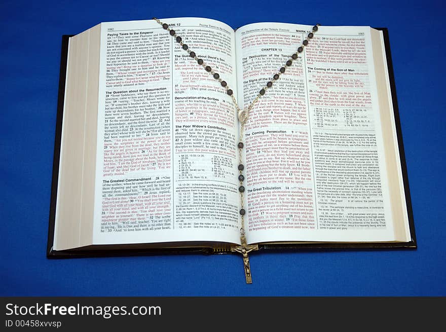 Holy Bible and rosary on blue background