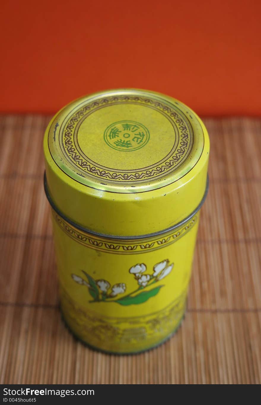 Old Chinese tea tin on bamboo with orange background. Old Chinese tea tin on bamboo with orange background