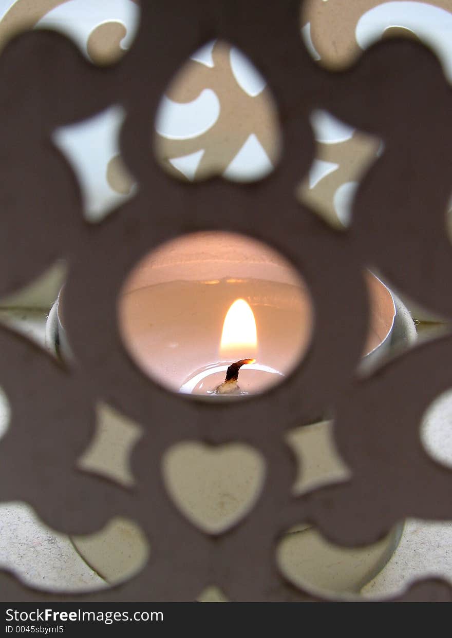 Candle burning in an old holder. (shallow focus on the flame). Candle burning in an old holder. (shallow focus on the flame)