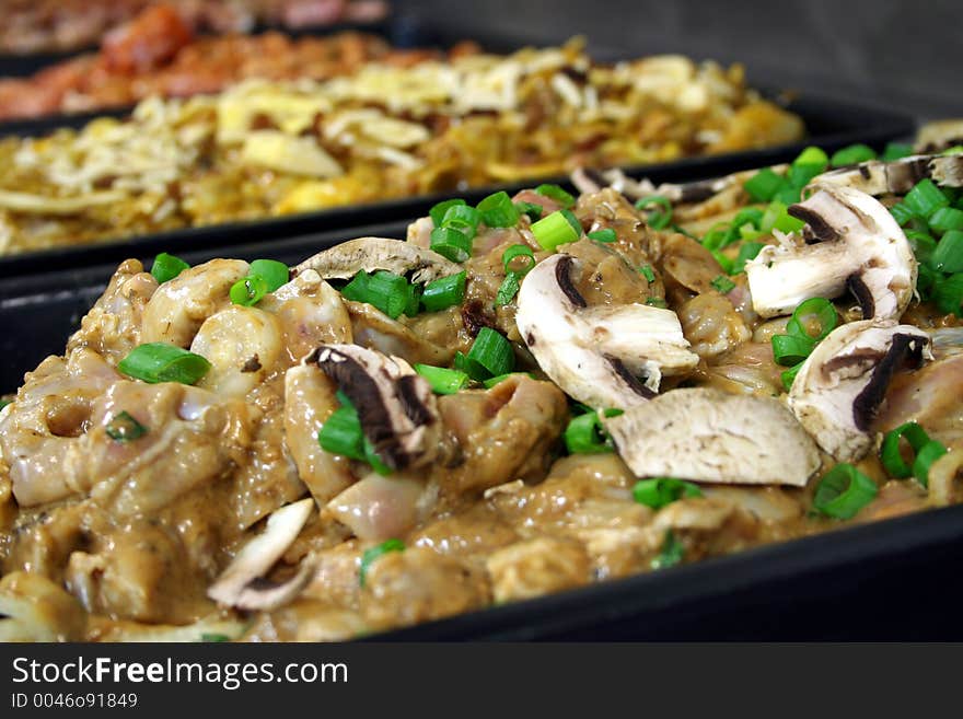 Several trays of different uncooked chicken mixtures freshly prepared close up. Several trays of different uncooked chicken mixtures freshly prepared close up