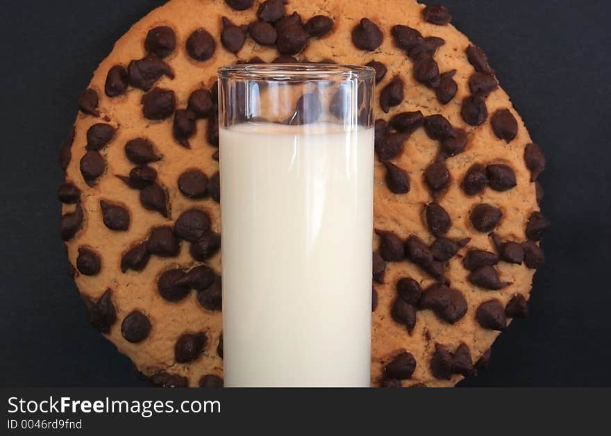 Image of a giant chocolate cookie dwarfing a glass of milk. Image of a giant chocolate cookie dwarfing a glass of milk