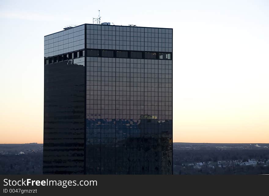 Dawn is rising over a modern dark glass skyscraper. Can be used to illustrate the dawn of the modern age. Dawn is rising over a modern dark glass skyscraper. Can be used to illustrate the dawn of the modern age.