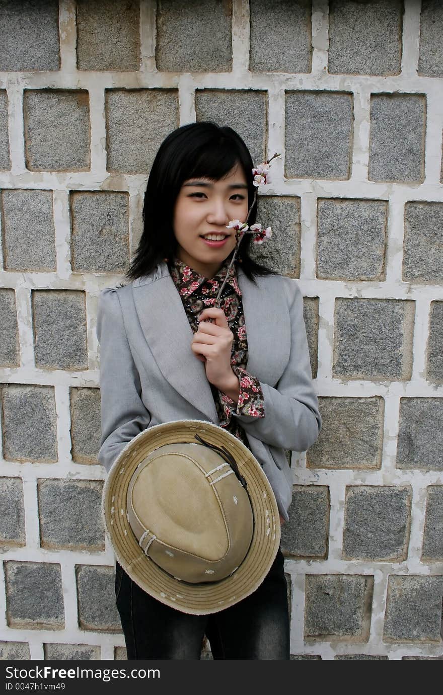 Stylish Asian girl holding a hat and flowers