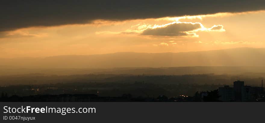 Sunset on the city with magic cloud lighting. Contryside and mountains in the back. Sunset on the city with magic cloud lighting. Contryside and mountains in the back.