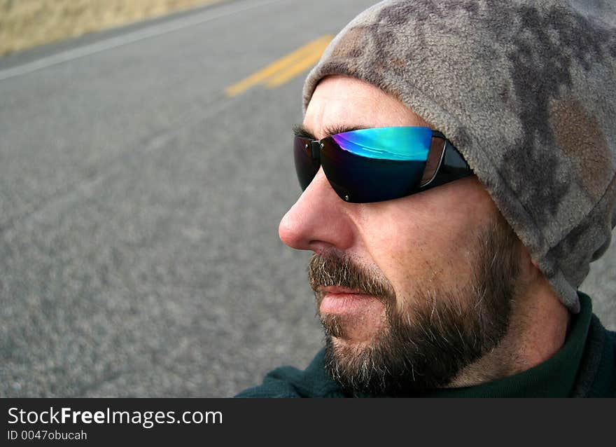 A middle-aged man with cool shades and a beanie looks forward to a road trip. Pavement and highway markings in the background. The sky and road ahead suggested in the reflection. For those who love to drive!. A middle-aged man with cool shades and a beanie looks forward to a road trip. Pavement and highway markings in the background. The sky and road ahead suggested in the reflection. For those who love to drive!