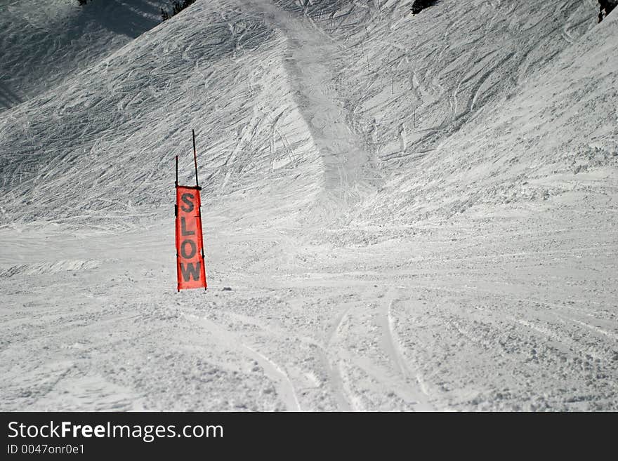 This is an orange sign you see on a ski slope. It is made of a see-through mesh material. Obviously used to caution skiiers to slow down. This is an orange sign you see on a ski slope. It is made of a see-through mesh material. Obviously used to caution skiiers to slow down.