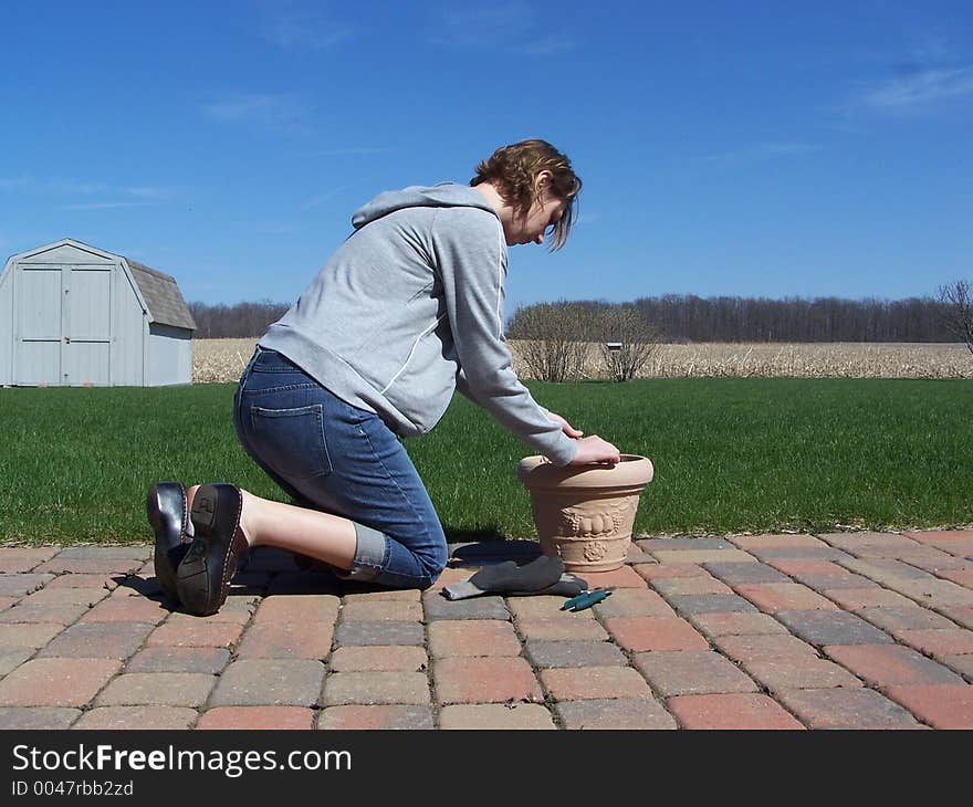 Photo of a woman preparing her potted plant for spring underneath a blue sky. Photo of a woman preparing her potted plant for spring underneath a blue sky.