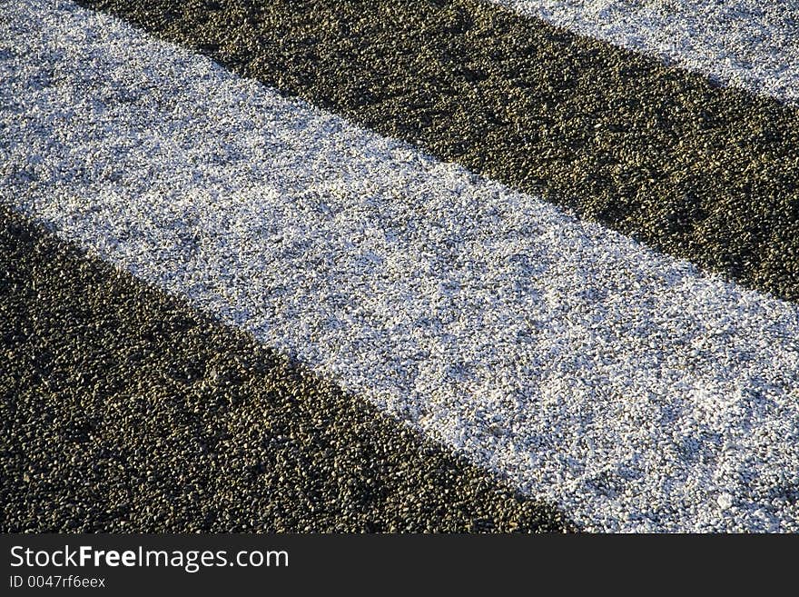 Gravel from a building roof with a painted white stripe. Gravel from a building roof with a painted white stripe