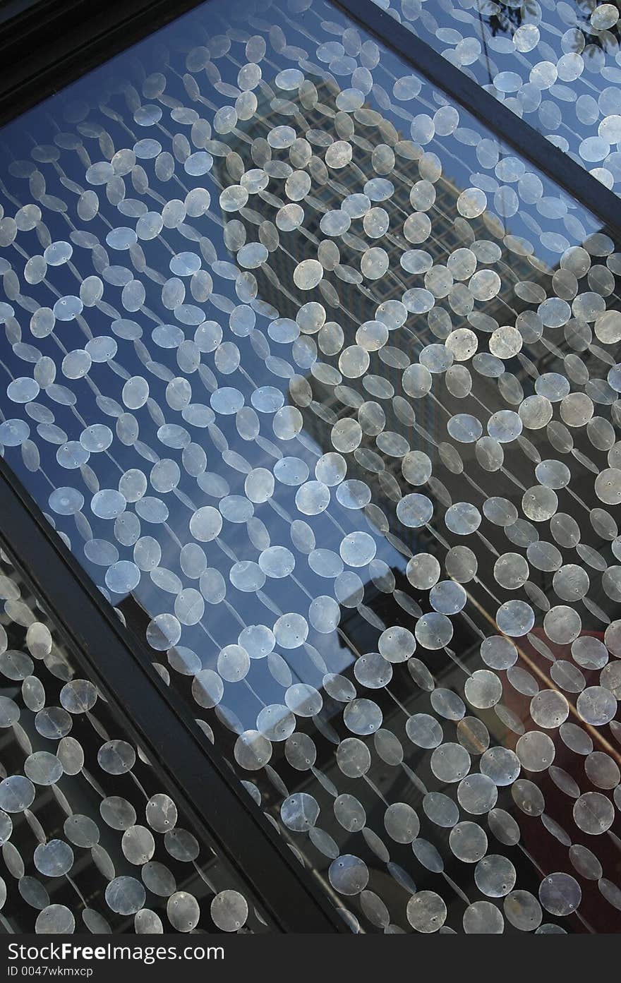 Glittery beads in window with highrise reflection in glass.