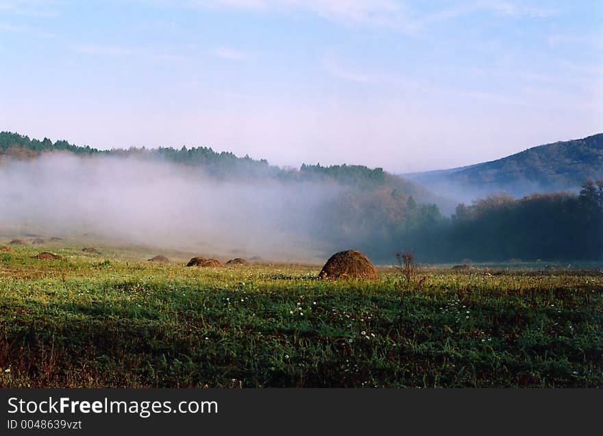 Meadow with stacks of hay in the fog in the morning. Meadow with stacks of hay in the fog in the morning