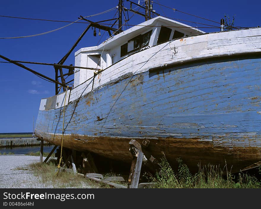 A damaged boat rotting away on the edge of the water.