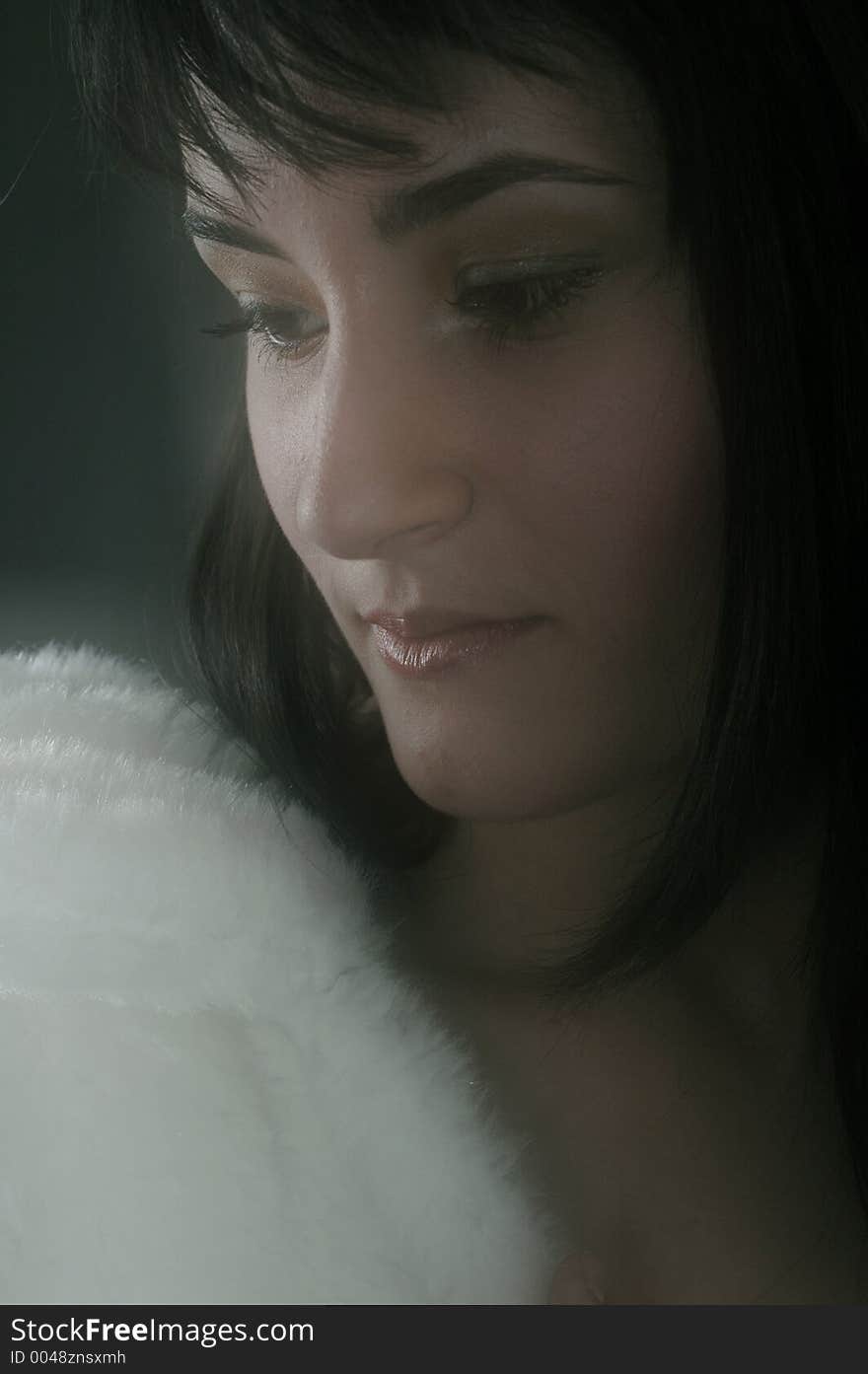 Beautiful young woman feeling comfortable in her white fur coat, in soft glow. Beautiful young woman feeling comfortable in her white fur coat, in soft glow.