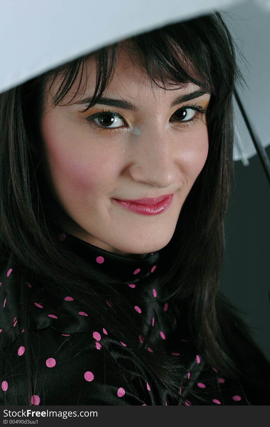 Pretty young brunette woman smiling from under an umbrella. Pretty young brunette woman smiling from under an umbrella.