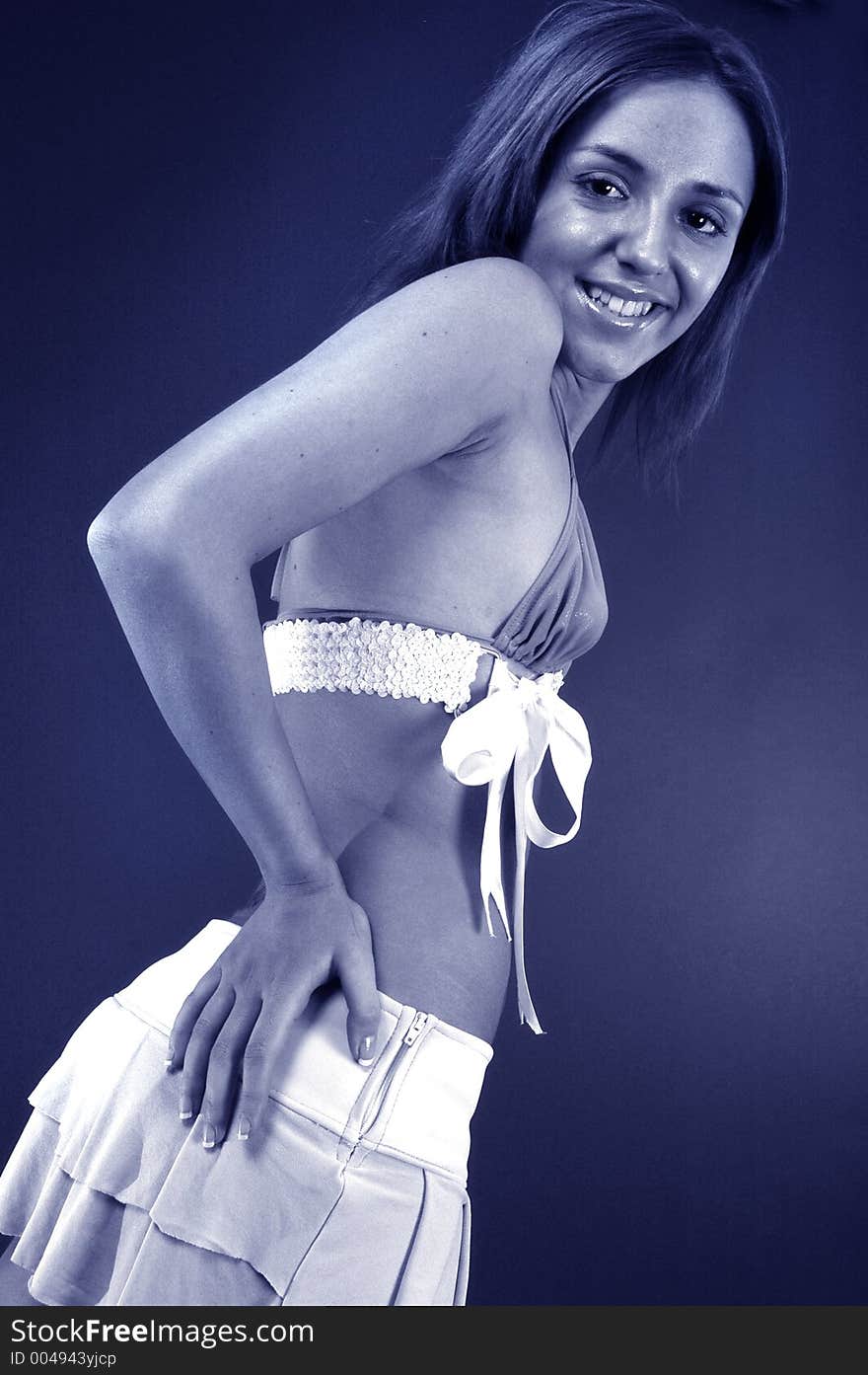 Beautiful young woman with her hands on her hips smiling happily, in blue tint.