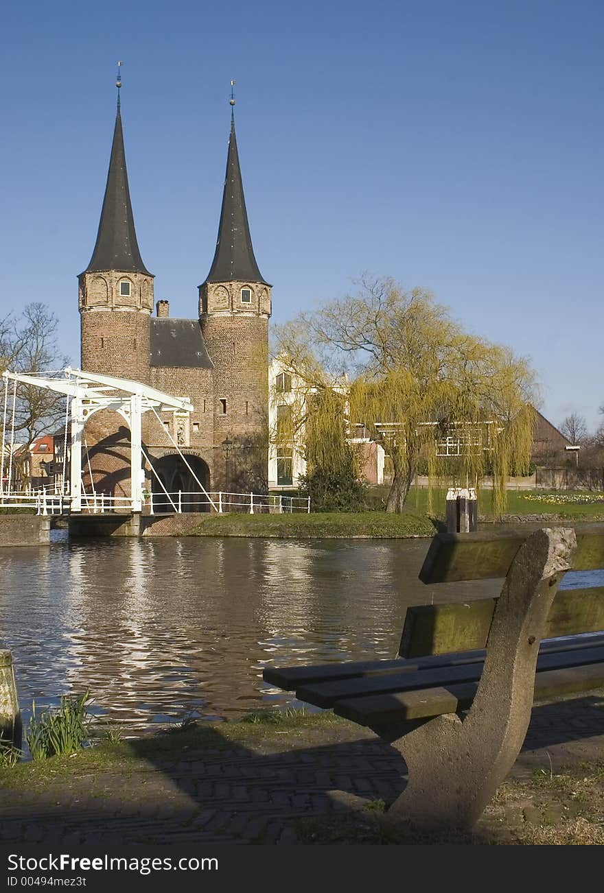 Old city gate and bridge with bench in foreground. Old city gate and bridge with bench in foreground