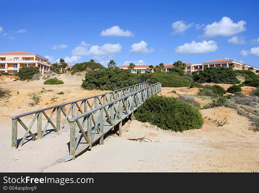 Wooden walkway on sandy beach in Spain leading to luxury hotel