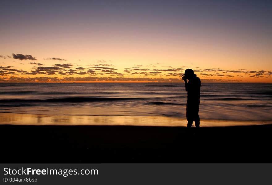 Silhouette of a photographer taking a picture of the sunrise on the beach. Silhouette of a photographer taking a picture of the sunrise on the beach