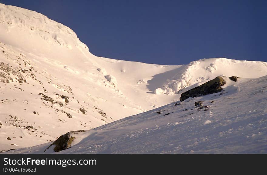 Snow-covered mountains. Winter mountain landscape. Snow on a mountain covered by the sun. Snow-covered mountains. Winter mountain landscape. Snow on a mountain covered by the sun.