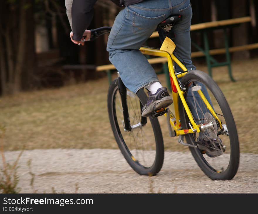 A young man races along a gravel path on his mountain bike. A young man races along a gravel path on his mountain bike