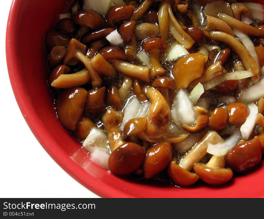 Marinaded mushrooms with onion and oil in the red bowl.