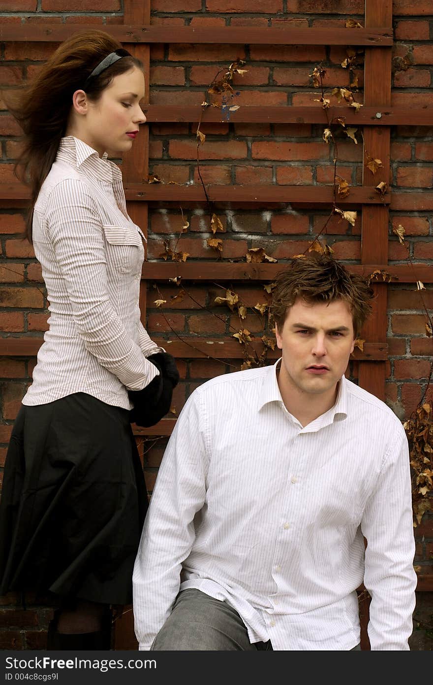 A Couple in white posing in front of brick wall. A Couple in white posing in front of brick wall