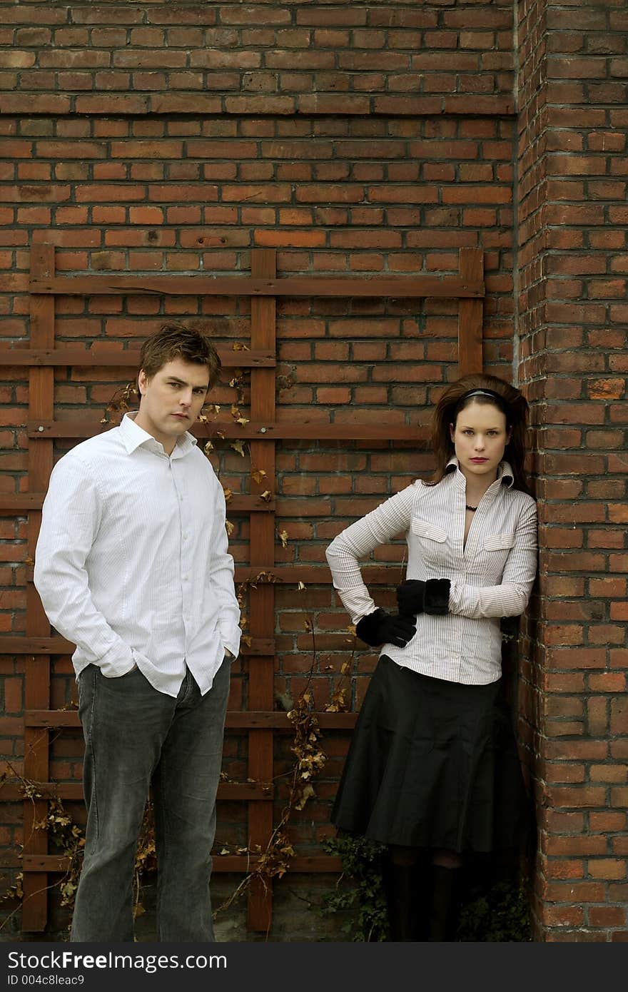 A couple posing in front of a brick wall. A couple posing in front of a brick wall