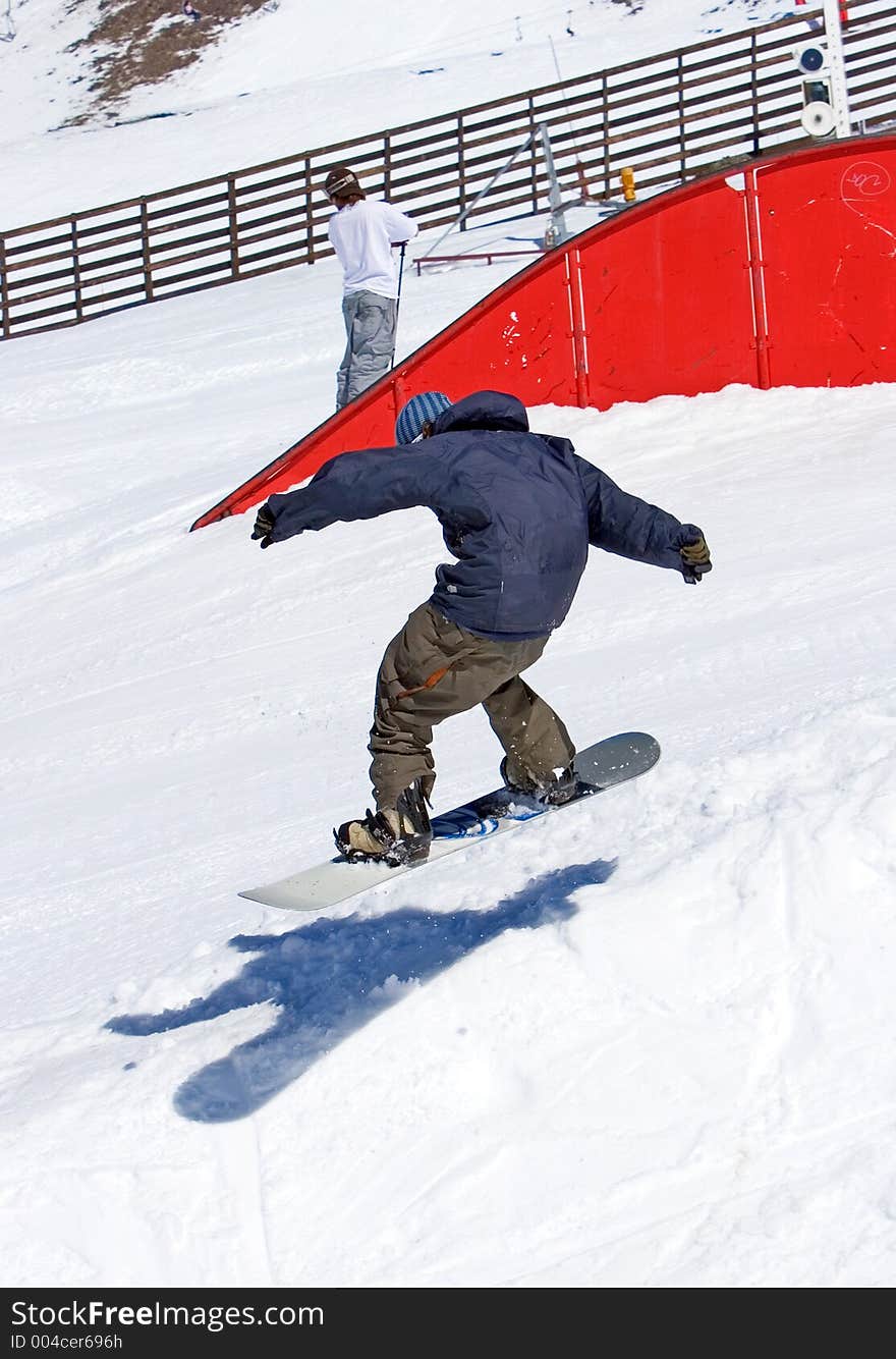 Snowy ski slopes of Pradollano ski resort in the Sierra Nevada mountains in Spain with snowboarder in half pipe. Snowy ski slopes of Pradollano ski resort in the Sierra Nevada mountains in Spain with snowboarder in half pipe